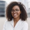 Smiling african-american businesswoman in a city. Mixed race girl looking at camera. People, city life, student lifestyle concept