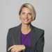 Portrait of smiling mature businesswoman standing against grey background.