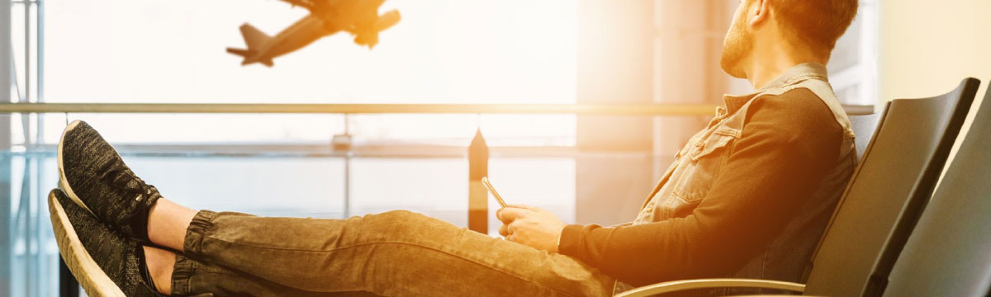 man sitting at airport lounge with plane outside window